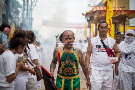 PHUKET, THAILAND - SEPTEMBER 30: Unidentified Mah song pierced weapon to their cheeks, They believed to suffer the pain of devotee during the Phuket Vegetarian Festival. The Festival is a famous annual festival also known as Nine Emperor Gods festival on のeditorial素材