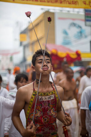 PHUKET, THAILAND - SEPTEMBER 30: Unidentified Mah song pierced weapon to their cheeks, They believed to suffer the pain of devotee during the Phuket Vegetarian Festival. The Festival is a famous annual festival also known as Nine Emperor Gods festival on のeditorial素材