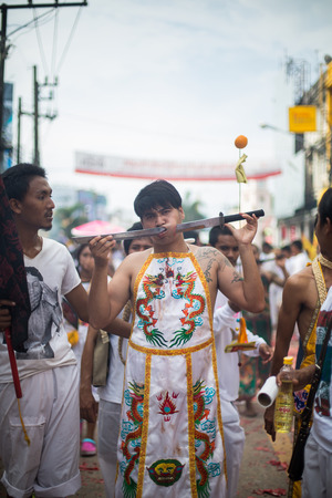 PHUKET, THAILAND - SEPTEMBER 30: Unidentified Mah song pierced weapon to their cheeks, They believed to suffer the pain of devotee during the Phuket Vegetarian Festival. The Festival is a famous annual festival also known as Nine Emperor Gods festival on のeditorial素材