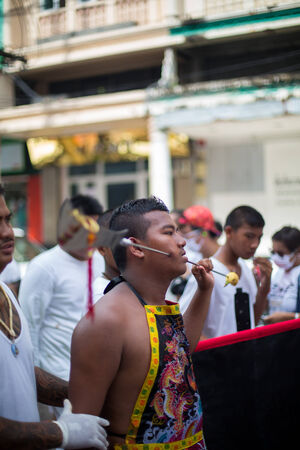 PHUKET, THAILAND - SEPTEMBER 30: Unidentified Mah song pierced weapon to their cheeks, They believed to suffer the pain of devotee during the Phuket Vegetarian Festival. The Festival is a famous annual festival also known as Nine Emperor Gods festival on のeditorial素材