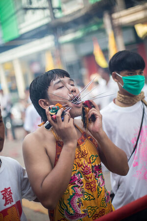 PHUKET, THAILAND - SEPTEMBER 30: Unidentified Mah song pierced weapon to their cheeks, They believed to suffer the pain of devotee during the Phuket Vegetarian Festival. The Festival is a famous annual festival also known as Nine Emperor Gods festival on のeditorial素材
