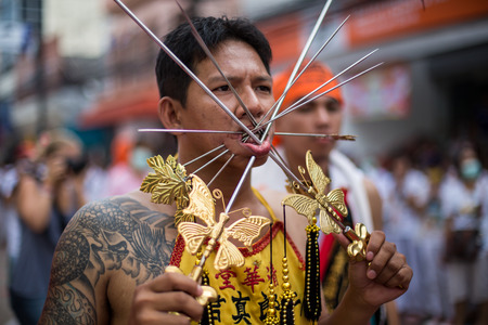 PHUKET, THAILAND - SEPTEMBER 30: Unidentified Mah song pierced weapon to their cheeks, They believed to suffer the pain of devotee during the Phuket Vegetarian Festival. The Festival is a famous annual festival also known as Nine Emperor Gods festival on のeditorial素材