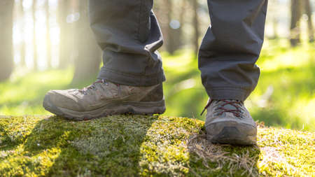 person walking through the forest in nature. Healthy life style. Boots in the foregroundの写真素材