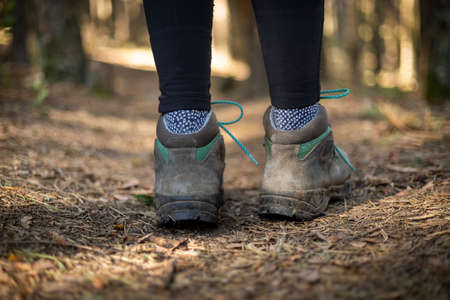 person walking through the forest in nature. Healthy life style. Boots in the foregroundの写真素材