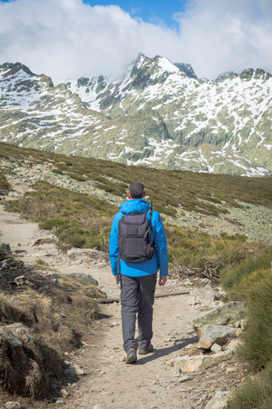 Person with backpack walking down the mountain on a sunny day. Circo de Gredos, national park in...