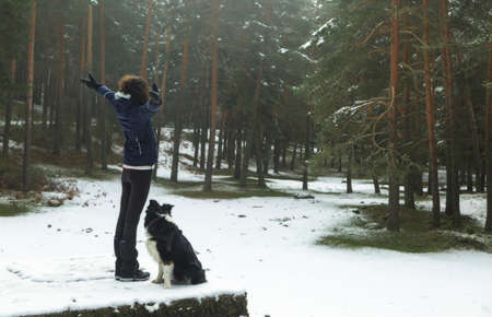 Woman and dog enjoying themselves in the middle of a snowy forest. In the Sierra de Guadarrama National Park, El Espinar, Segovia, Madrid.の写真素材