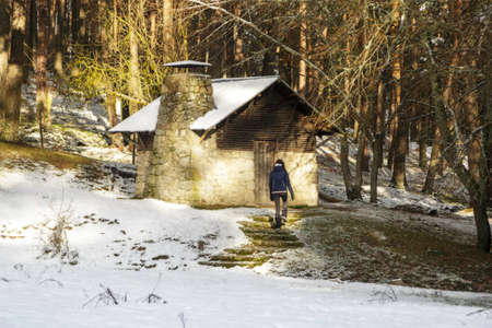 Woman walking alone towards a wooden cabin in the middle of a snowy forest. Refuge in the Sierra de Guadarrama National Park, El Espinar, Segovia, Madrid.の写真素材