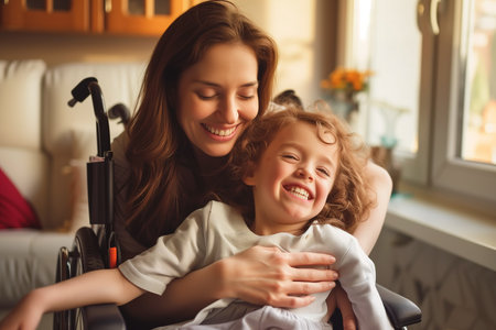 Portrait of a loving mother hugging one happy mentally disabled child in a wheelchair at her house with natural light. Happy people, example of improvementの素材