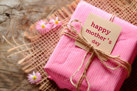 Small pink gift on background with white flowers and copy space. Happy Mother's Day, Love you mom. International Mother's Day, Banner for Mother's day.の素材