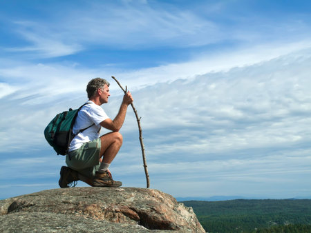 Mature Adult Man kneeling on rocky mountaintopの写真素材