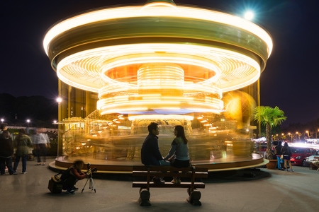 PARIS, FRANCE - MAY 17, 2014: Couple of spouses in front of Illuminated vintage carousel close to Eiffel Tower, Paris.のeditorial素材