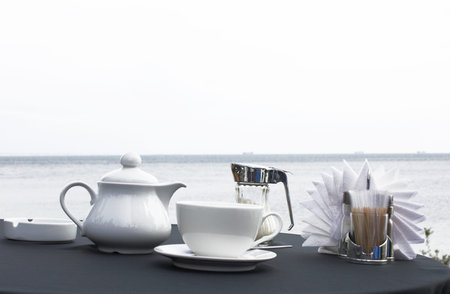 Cup of tea and teapot on table on seacoast