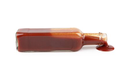 bottle of hot sauce is spilling liquid on white backgroundの写真素材