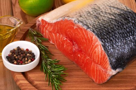 Salmon steak on a board on wooden tableの写真素材
