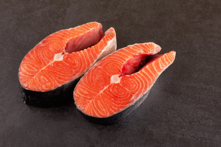  Two raw salmon steaks on a black background 