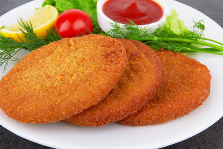 Fish pancakes on plate with ketchup, on dark surfaceの写真素材