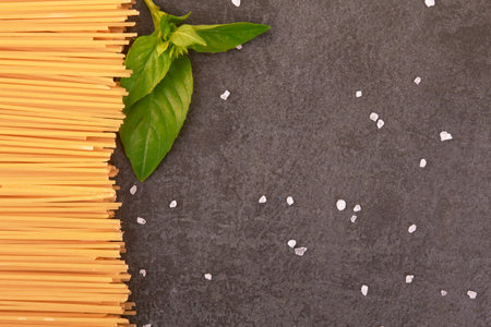 spaghetti on a stone black background with basilの写真素材