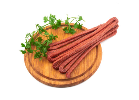 Smoked sausage on a wooden cutting board isolated on whiteの写真素材