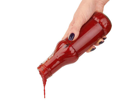 Bottle of ketchup in hand isolated on white backgroundの写真素材