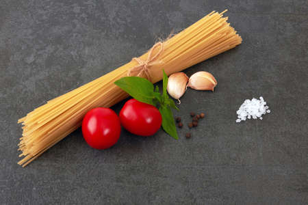 Spaghetti on a stone black background with basilの写真素材