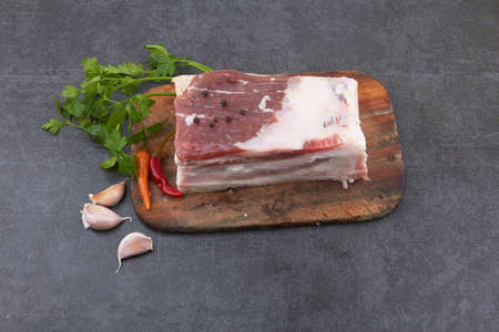 Raw pork belly with streaks of fat with slices on a wooden cutting boardの写真素材