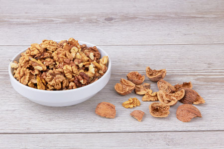 Walnuts in white bowl on wooden surface