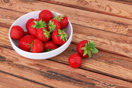 Strawberries in a saucer on a wooden backgroundの写真素材