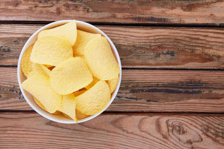 Potato chips on a wooden surface in a saucerの写真素材