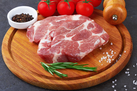 Raw meat with tomatoes on a black surfaceの写真素材