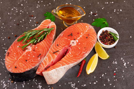 Salmon steak on a black background with spicesの写真素材