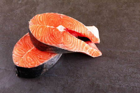 Two raw salmon steaks on a black backgroundの写真素材