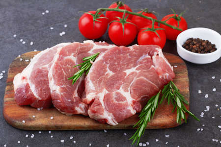 Raw meat with tomatoes on a black surfaceの写真素材