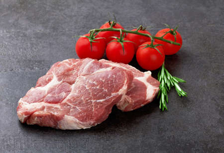 Raw meat with tomatoes on a black surfaceの写真素材