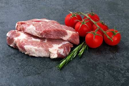 Raw meat with tomatoes on a black surfaceの写真素材