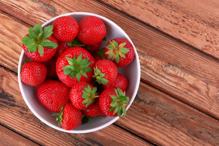 Strawberries in a saucer on a wooden backgroundの写真素材