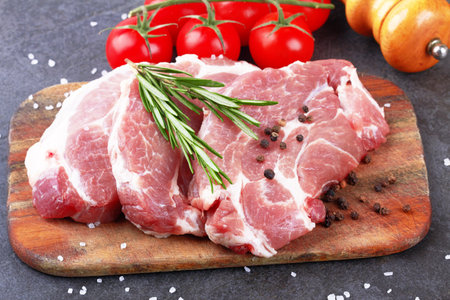 Raw meat with tomatoes on a black surfaceの写真素材