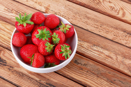 Strawberries in a saucer on a wooden backgroundの写真素材