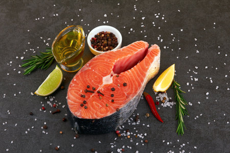 Salmon steak on a black background with spicesの写真素材