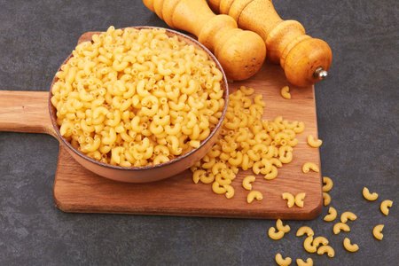 Elbow macaroni in bowl on black backgroundの写真素材
