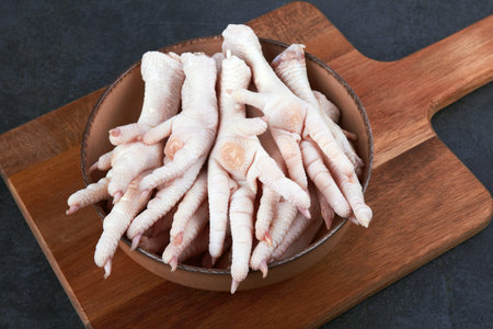 Raw chicken feet in bowl on black backgroundの写真素材