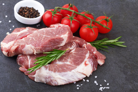 Raw meat with tomatoes on a black surfaceの写真素材