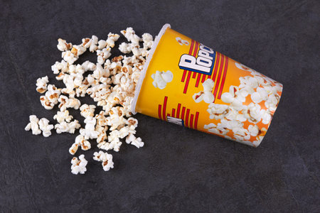 Scattered popcorn from yellow bucket on dark backgroundの写真素材