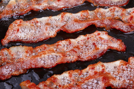 Fried bacon in a frying pan on as a backgrondの写真素材
