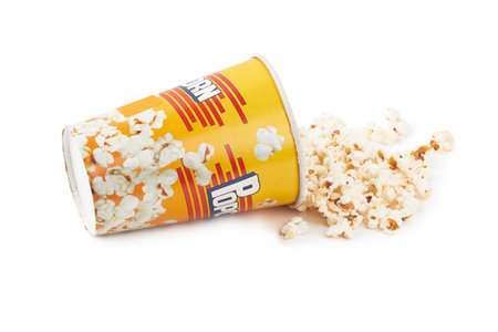 Scattered popcorn from yellow bucket isolated on white backgroundの写真素材