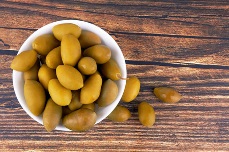 Green olives in bowl on wooden backgroundの写真素材