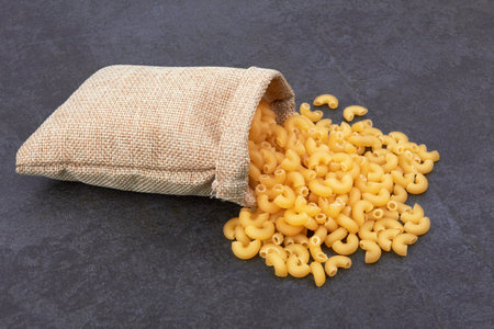Elbow macaroni in bag on black backgroundの写真素材