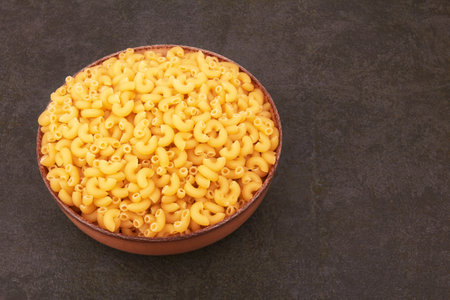 Elbow macaroni on a stone black backgroundの写真素材