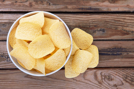 Potato chips on a wooden surface in a saucerの写真素材