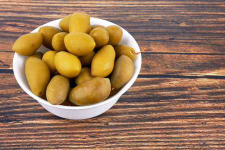 Green olives in bowl on wooden backgroundの写真素材