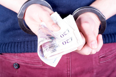 a picture of a criminal locked in handcuffs trying to bribe